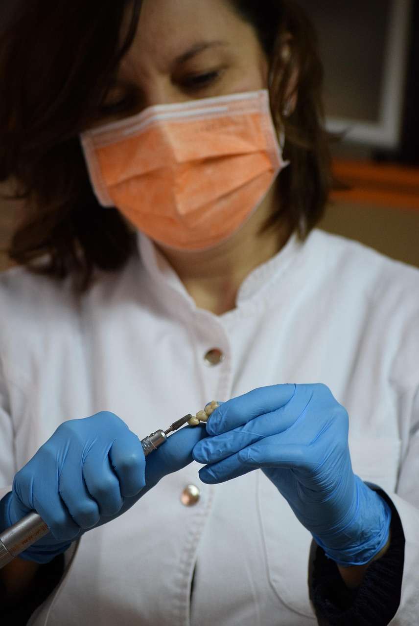 Dentist preparing a dental restoration in a clinical setting while wearing protective equipment, representing Orthodontist loans, pediatric dental financing, dental implant center funding, dental working capital loans, and oral surgeon startup loans for growing specialty dental practices.