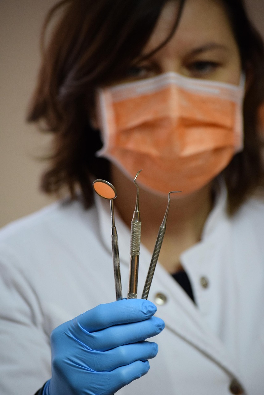 Dentist holding professional dental instruments in a clinical setting, representing Dental loans, dental succession planning financing, dental practice growth financing, oral surgery equipment financing, and implant equipment financing for modern dental practices.
