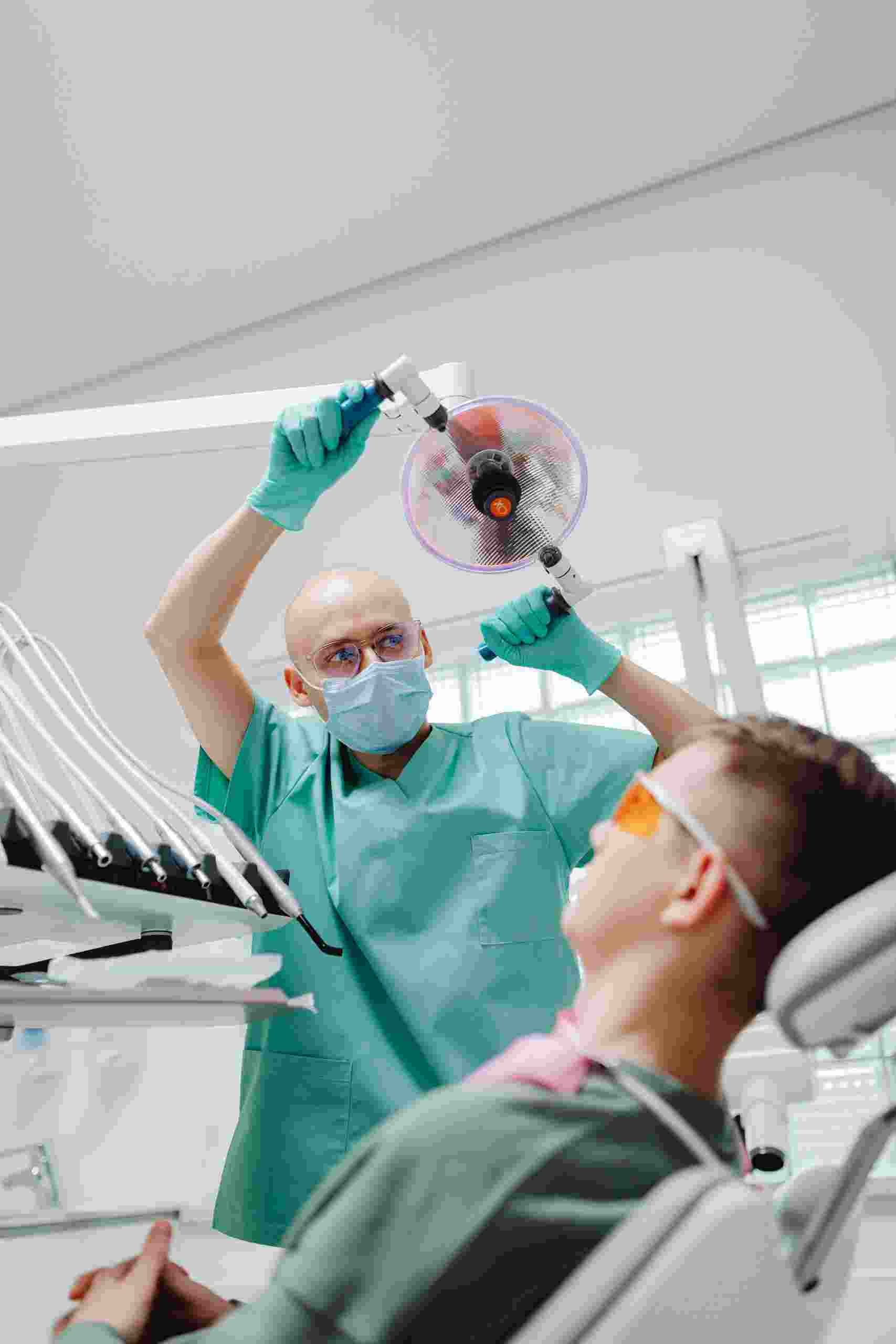 Dentist examining a patient under a dental treatment light in a modern clinic, showcasing Dental XRay Financing, Dental Startup Financing, Dental Practice Startup Loans, Superb Dental Clinic Startup Capital, and Startup Funding for Dentists used to launch and equip new dental practices.
