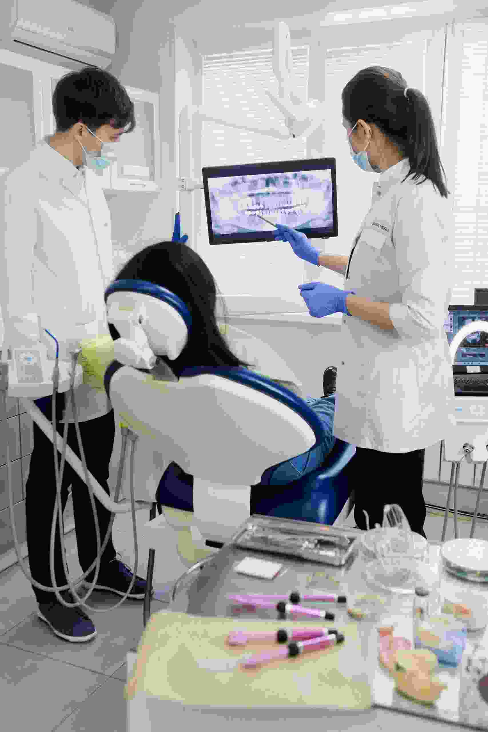 Modern dental clinic with dentists reviewing digital imaging beside a treatment chair, highlighting Dental Practice Loans, dental equipment financing, first dental practice financing, dental practice buyout loans, and multi location dental financing for growing dental businesses.